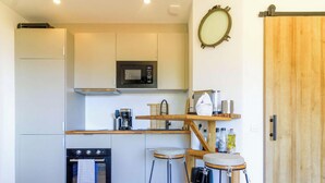 A compact kitchen with a microwave, coffee maker, and wooden stools. - Apartment, pets welcome, sea view - 4 guests (Le Lavandou)