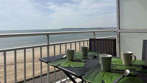 Ein Balkon mit Tisch für zwei Personen, Blick auf Strand und Meer.