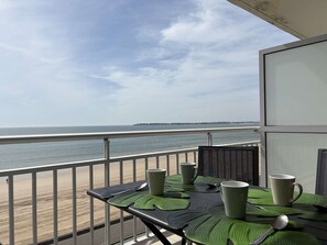 Ein Balkon mit Tisch für zwei Personen, Blick auf Strand und Meer.