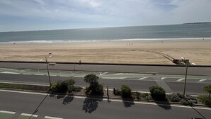 Blick auf einen Strand von einer erhöhten Position aus, mit blauem Himmel und ruhiger See.