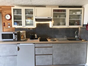 A modern kitchen with a microwave, coffee maker, kettle, and a sink with a dish rack. - Cozy cabin studio - 4 guests (Arâches-la-Frasse)