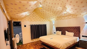 Un dormitorio con cama, mesita de noche, lámpara, ventilador y techo estampado.