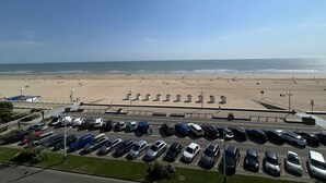 Ein Parkplatz mit Autos und einem Strand im Hintergrund.