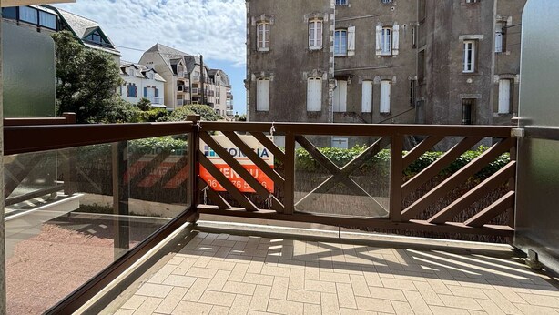 Ein Balkon mit Blick auf ein Gebäude mit mehreren Fenstern und Balkonen.