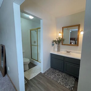Ein Badezimmer mit Dusche, Toilette, Waschbecken und Spiegel.