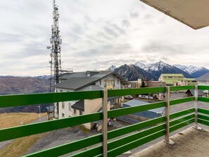Vista de la montaña con edificios, una torre de comunicaciones y una barandilla verde.