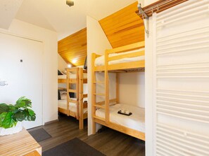 Una habitación con literas, una planta en maceta y un escritorio de madera.