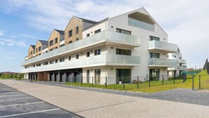 A multi-story hotel with a modern design, featuring balconies and a parking area. - Luxury Apartment with a Balcony | Balcony (Władysławowo)