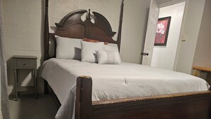 Une chambre à coucher avec un lit à baldaquin en bois, une table de chevet, un tapis et un tableau encadré au mur.