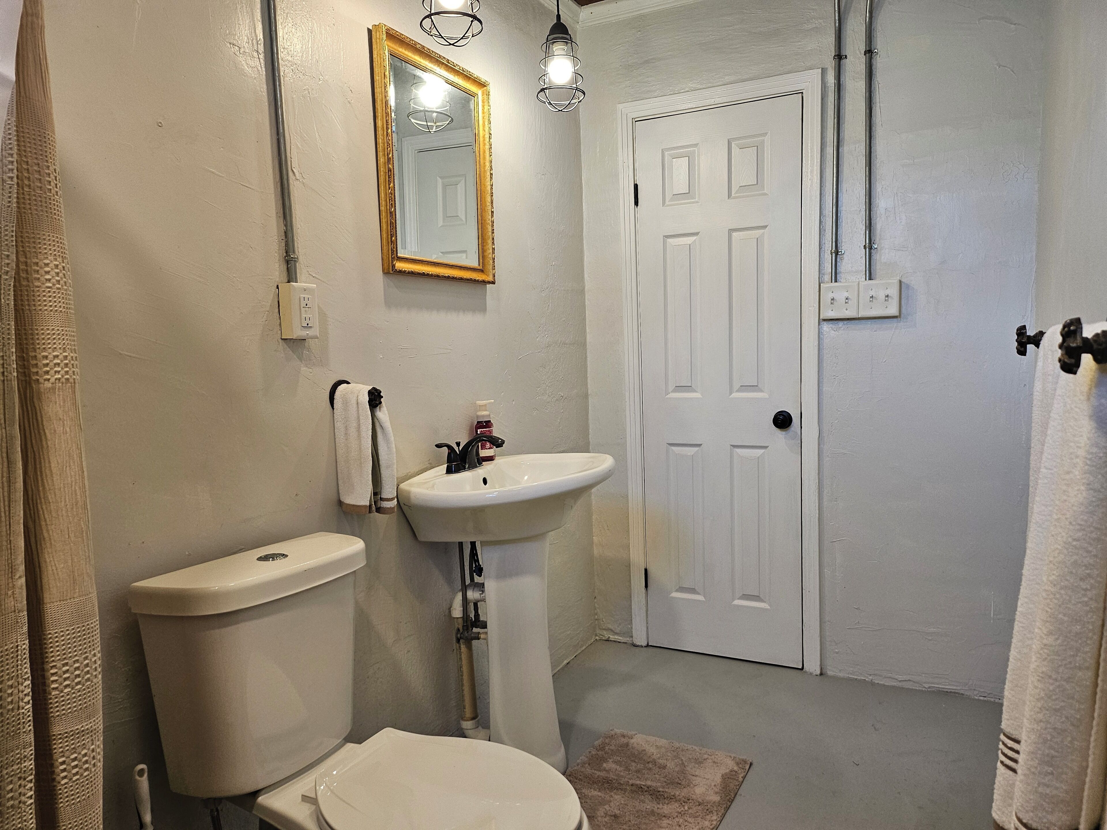 Een badkamer met toilet, wastafel, spiegel en deur.