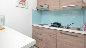 A modern kitchen with light wood cabinets, a stainless steel sink, and a countertop with a tablet. - Apartment with parking - 6 guests (Le Grau-du-Roi)