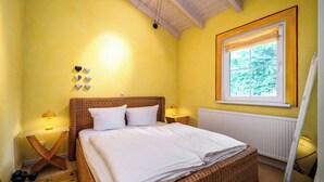 A room with a bed, a window with curtains, a radiator, and a mirror. - Kathi Vacation Home on Lake Jabelschen with a Garden, Terrace, and Fireplace (Jabel)
