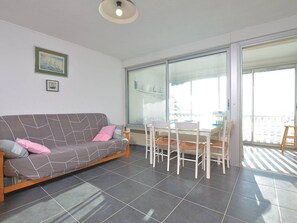 A living room with a sofa, chairs, a table, and a balcony with a view. - Apartment with sea view - 5 guests (Le Grau-du-Roi)