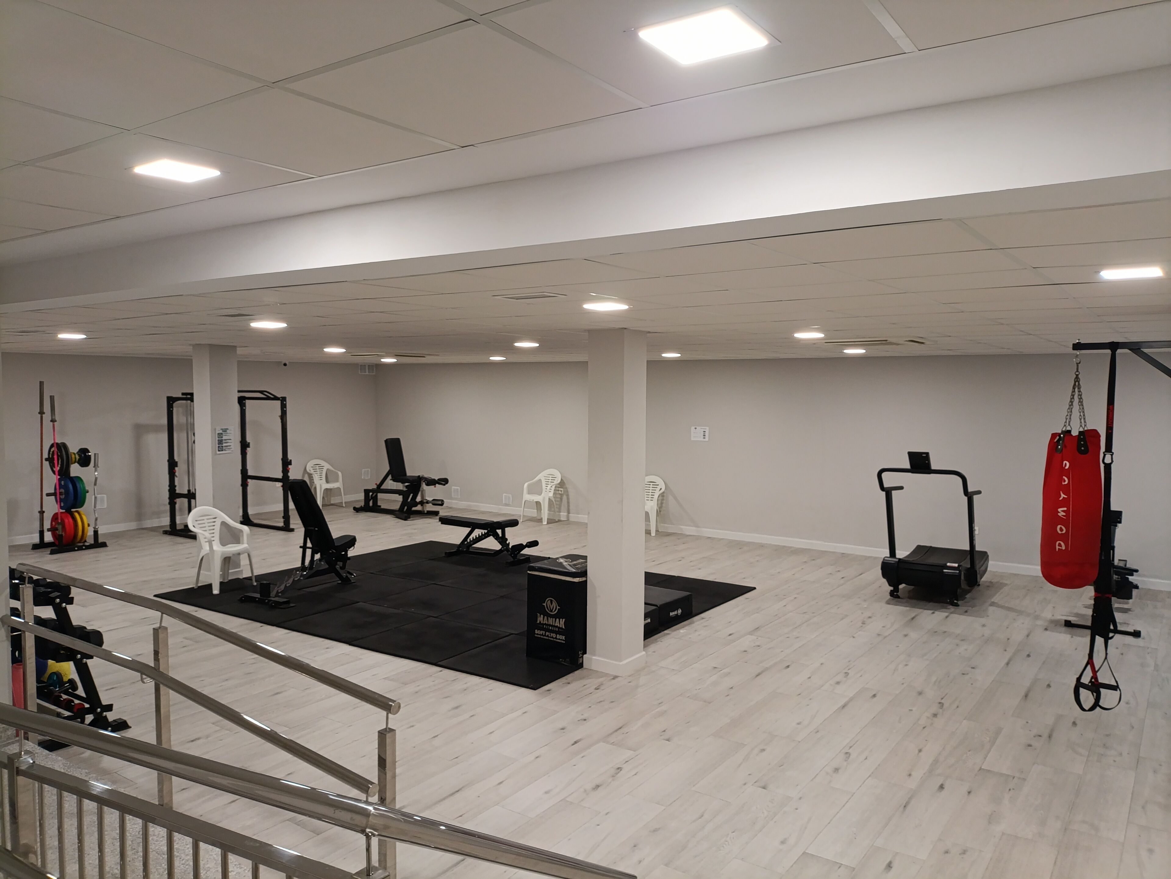 Un gimnasio con equipo de ejercicio variado, que incluye máquinas de pesas, bancos y un saco de boxeo.