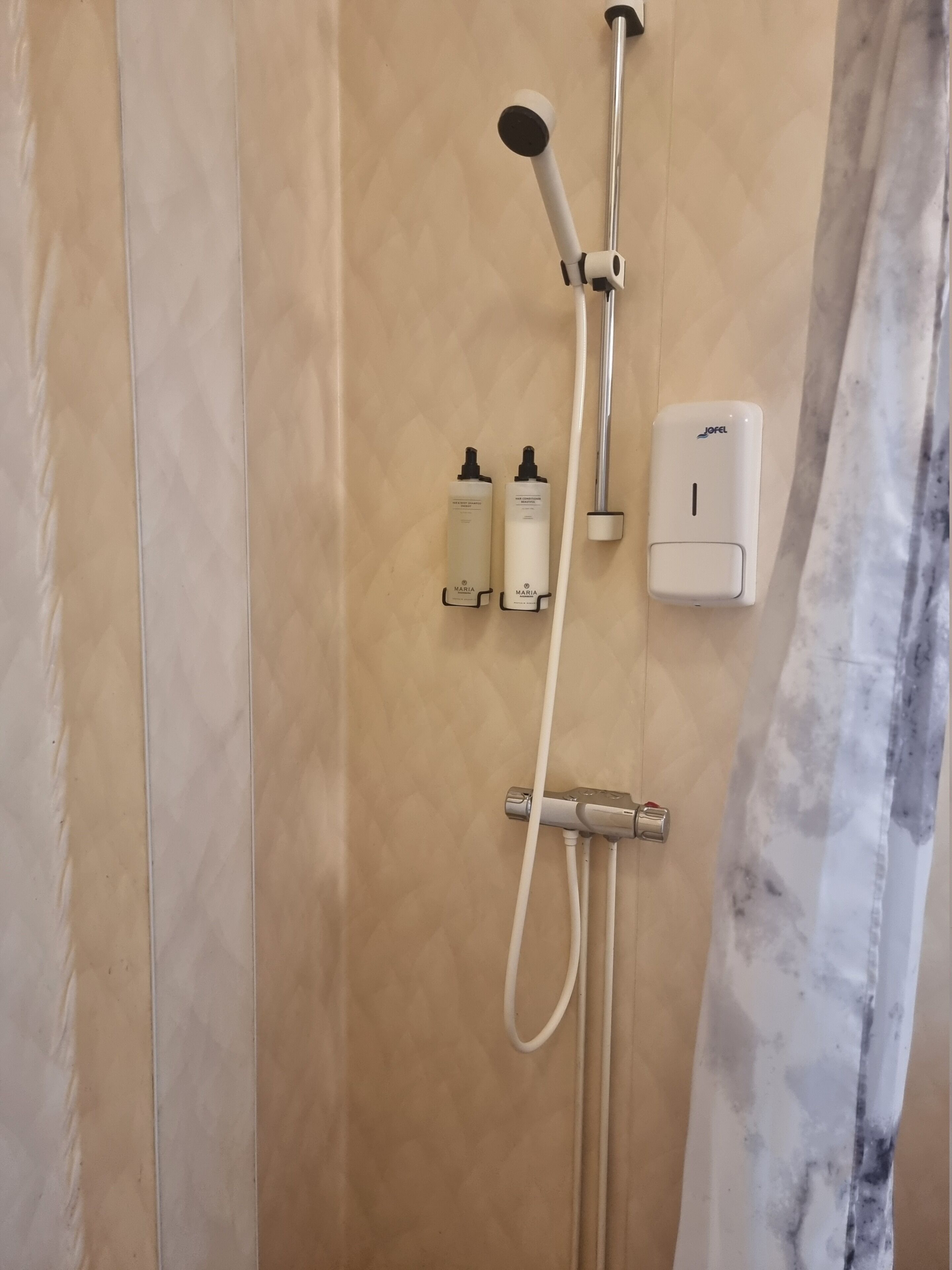 A shower with a handheld showerhead, a wall-mounted handheld showerhead, and a handheld soap dispenser.