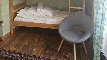 Una cama litera con una silla, suelo de madera y una alfombra estampada.