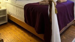 Una cama con dosel, cabecera de madera y colcha morada.