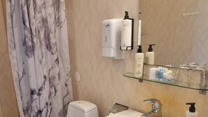Baño con inodoro, lavamanos y dispensador de jabón.