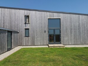 A modern building with a large glass door, a small window, and a door with a metal handle. - Fieldstone Barn (Okehampton)