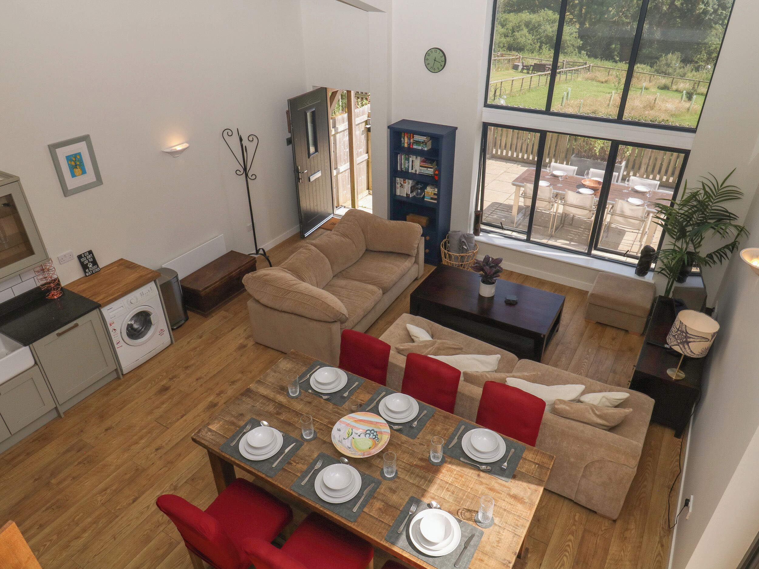 Una sala de estar moderna con comedor, sofá, estantería y vista al exterior.
