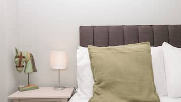 A bedroom with a bed, a nightstand, a lamp, and a decorative horse head.