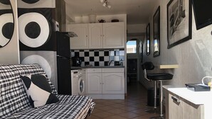 Un espacio habitable compacto con sofá, kitchenette, lavadora y zona de comedor.