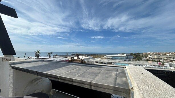 Una terraza en la azotea con vistas al mar y al paisaje urbano.
