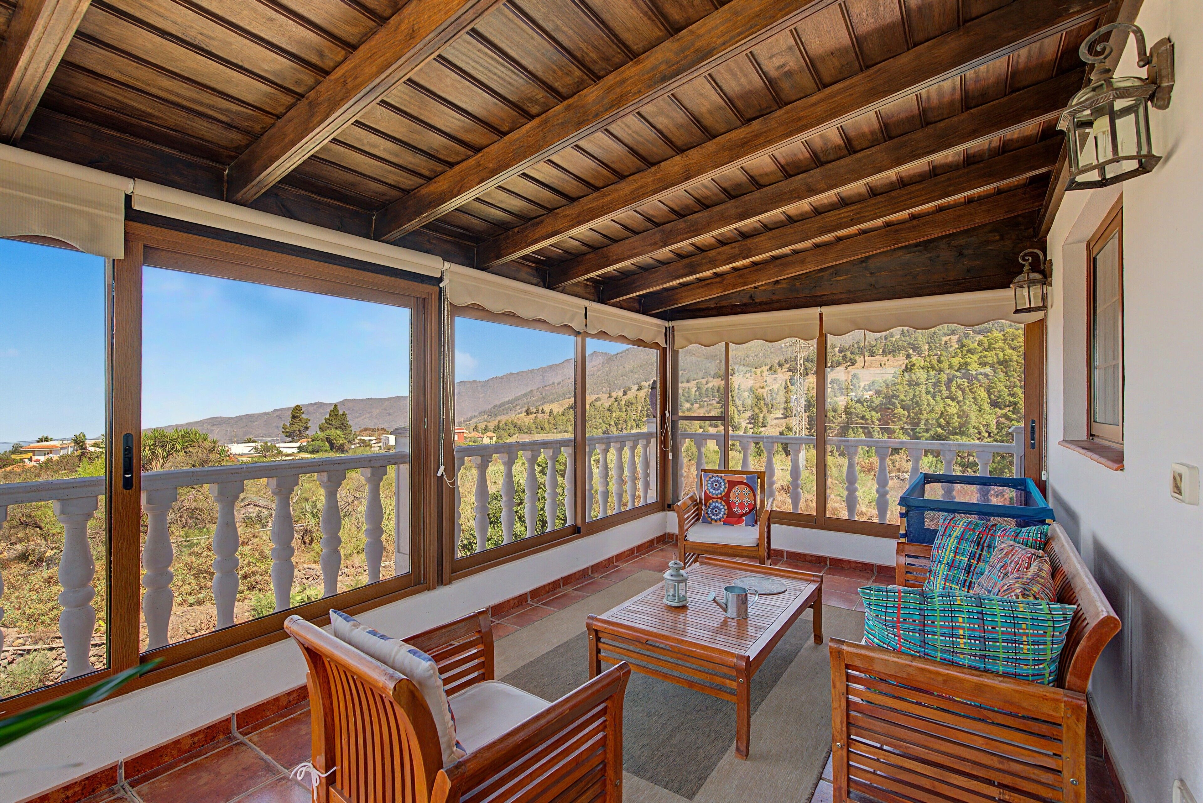 A covered outdoor seating area with a view of a mountainous landscape.