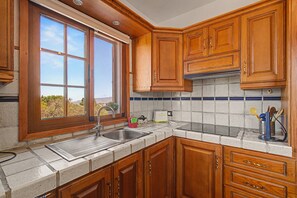 A kitchen with wooden cabinets, a stainless steel sink, and a window with a view of the outdoors. - Casa La Era La Palma Apartment with Mountain Views, Wi-Fi and Air Conditioning (El Paso)
