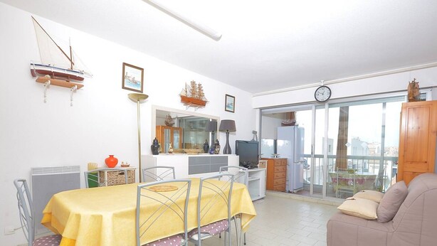 A living room with a dining table, sofa, and a balcony with a view.