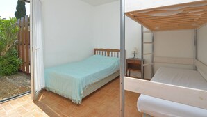 Une chambre avec un lit, une petite table avec une lampe et une vue sur un jardin.