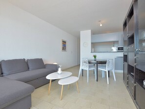 A modern living room with a grey sofa, a small white table, and two white chairs. - Apartment sea view with garage (Le Grau-du-Roi)