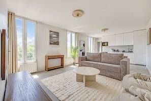 A spacious living area with a sofa, a coffee table, and a view of the kitchen. - Spacious Appartement 1br/4p - Aubervilliers (Aubervilliers)