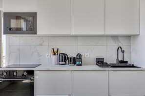 A modern kitchen with a built-in microwave, a coffee maker, a toaster, and a sink. - Spacious Appartement 1br/4p - Aubervilliers (Aubervilliers)