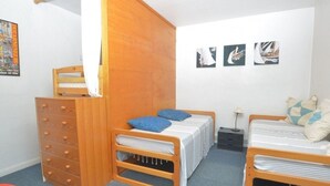 Ein Schlafzimmer mit zwei Betten, einer Holzkommode, einem Sessel und Wandbildern.