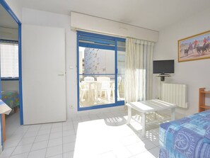 Ein Zimmer mit einem Bett, einem Fernseher, einem Tisch und einem Balkon mit Stühlen.