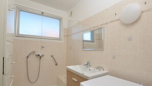 Une salle de bain avec une douche, un lavabo, des toilettes, une fenêtre et un miroir.