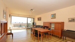 Une pièce comprenant une table à manger, des chaises, un canapé, un téléviseur et un meuble. Il y a un balcon avec vue.