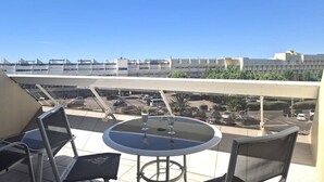 A balcony with a round table and two chairs, overlooking a parking lot and buildings. - Comfortable studio with air conditioning - Cap d'Agde (Cap d'Agde)