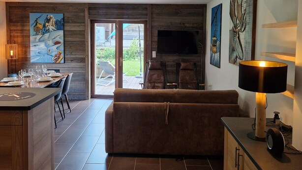 Ein modernes Wohnzimmer mit einer Couch, einem Essbereich mit Stühlen und einem Tisch, einem an der Wand befestigten Fernseher und einem Kamin.