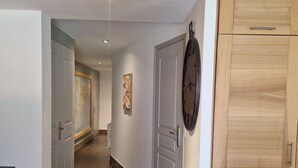 Ein Flur mit einem Holzkabinett, einer Tür mit einer Uhr und einem Gemälde an der Wand.