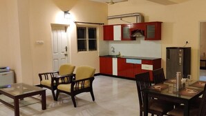 A compact living space with a dining area, a kitchenette, and a separate door leading to another room.