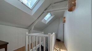 Ein Zimmer mit Oberlichtern, Holzboden, einer weißen Geländer und einer Lampe.