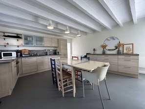 A modern kitchen with light wood cabinetry, a white dining table, and a ceiling with exposed beams. - Ideal house in peaceful location - 6 guests (Guérande)