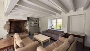 Ein Wohnzimmer mit Kamin aus Stein, einem grauen Schrank, einem Sofa, einem Couchtisch und einem Fenster mit Aussicht.
