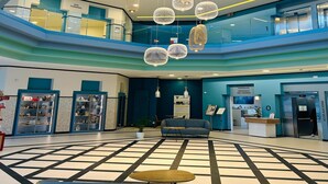 Un vestíbulo de hotel con un área de estar central, una recepción y un espacio termal para spa.