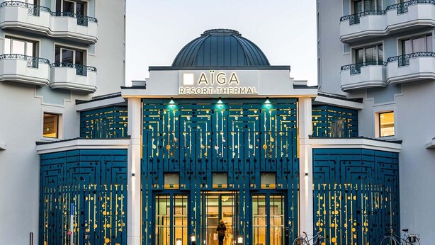 Un edificio con una cúpula y el letrero 'AIGA RESORT THERMAL' sobre la entrada.