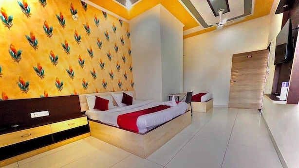 Una habitación de hotel moderna con una cama grande, un cabecero de madera, una pared con estampado de hojas, un armario y un piso de baldosas.