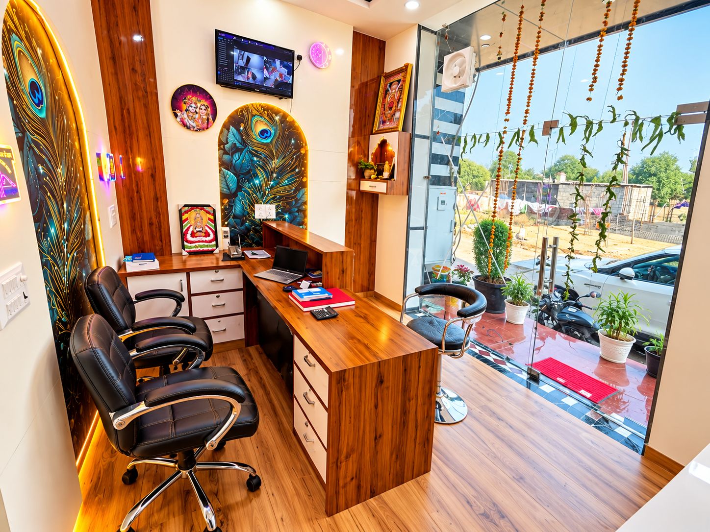 Ein modernes Büro mit Schreibtisch aus Holz, schwarzen Bürostühlen, einem Fernseher und Wanddekoration.