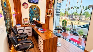 Ein modernes Büro mit Schreibtisch aus Holz, schwarzen Bürostühlen, einem Fernseher und Wanddekoration.